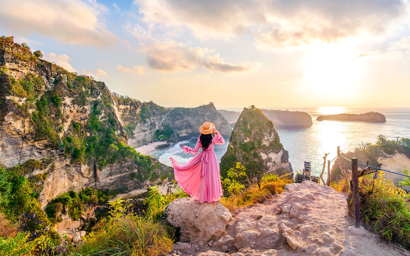 Tourist at viewpoint overlooking Diamond Beach cliffs, Nusa Penida, Indonesia.