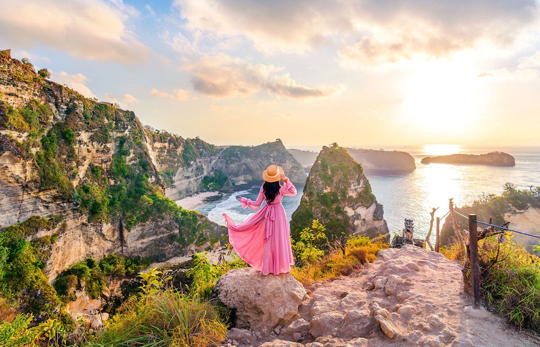 Tourist at viewpoint overlooking Diamond Beach cliffs, Nusa Penida, Indonesia.