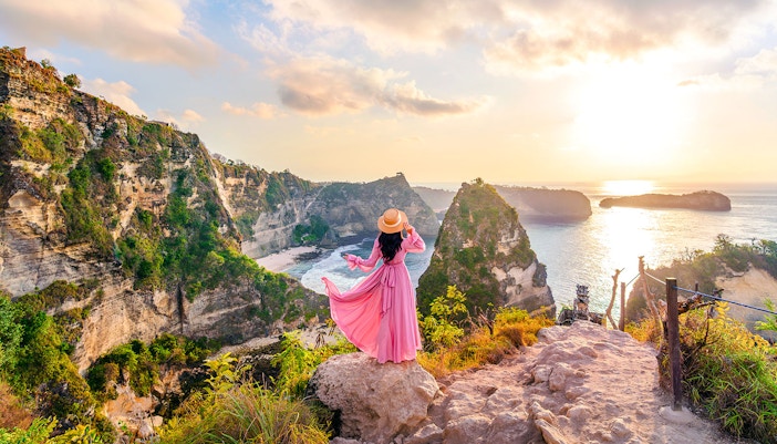 Tourist at viewpoint overlooking Diamond Beach cliffs, Nusa Penida, Indonesia.