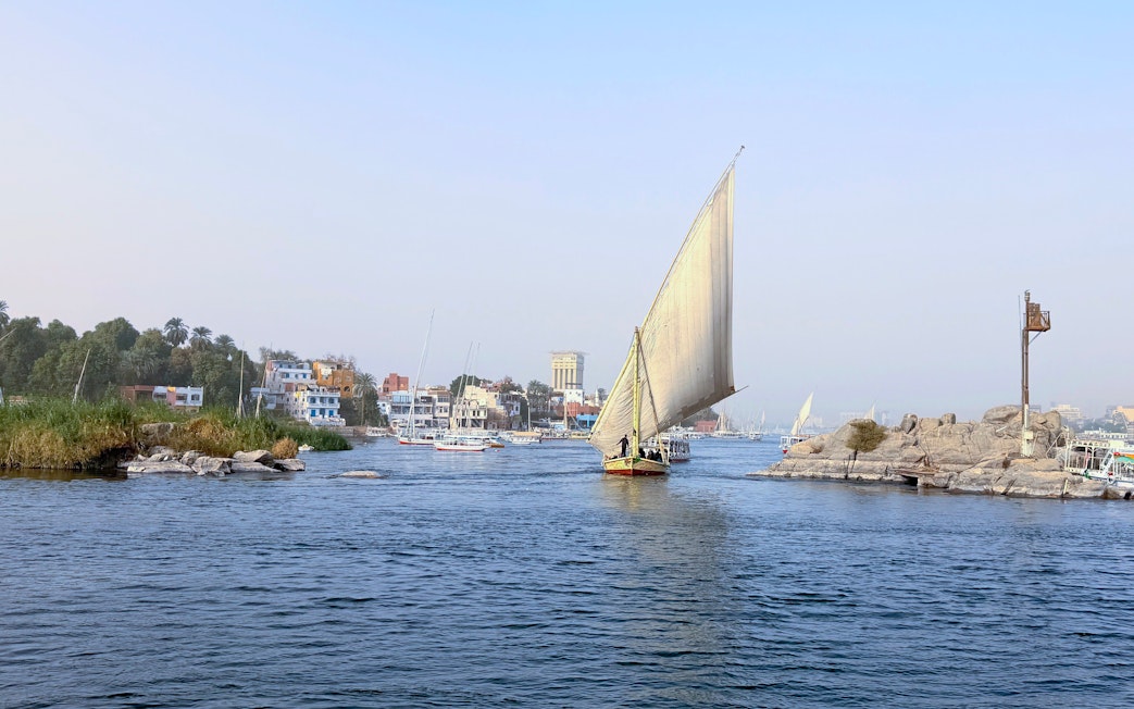 Felucca sailing on the Nile River with Cairo cityscape in the background.