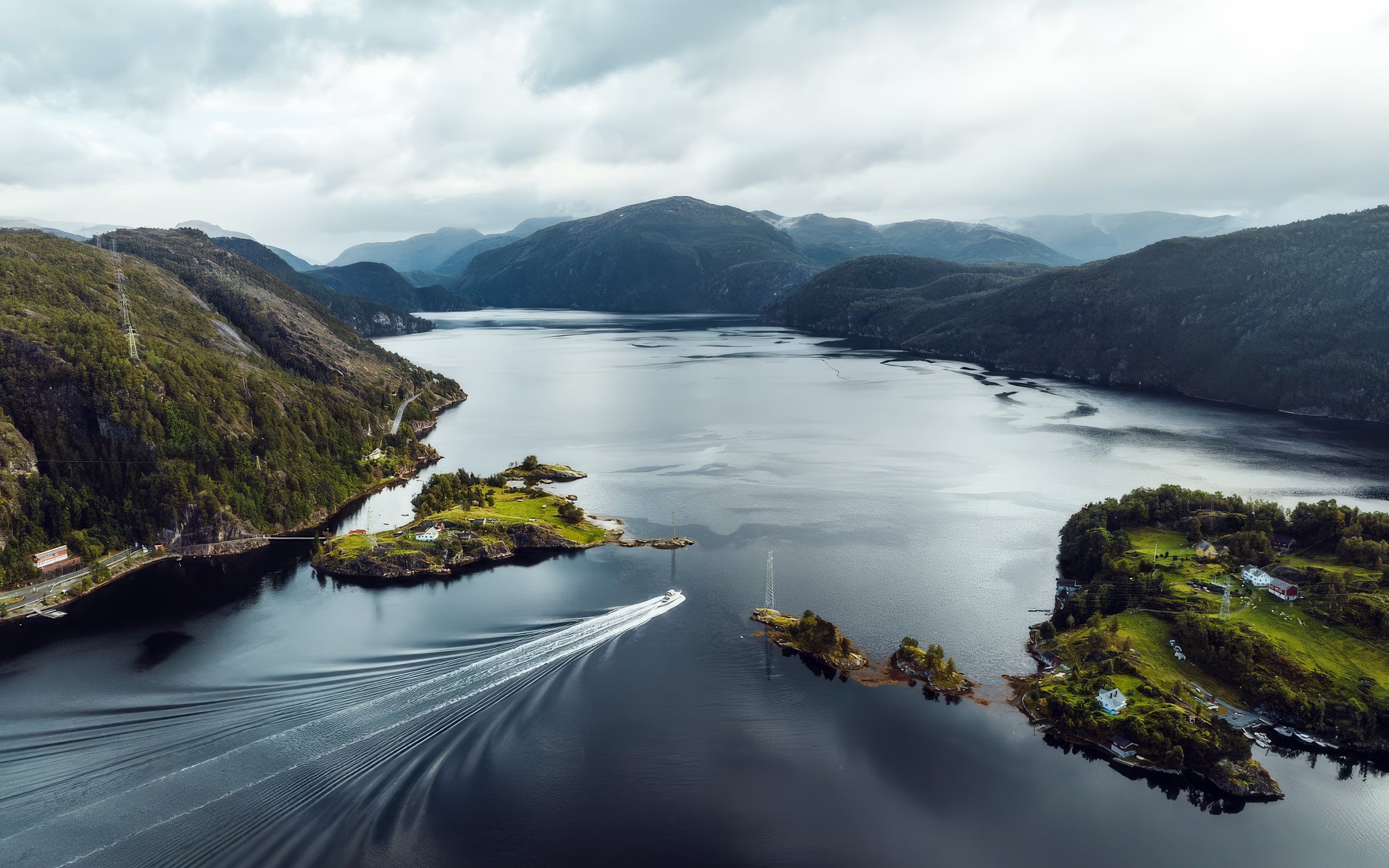 Aerial view of a Norwegian fjord with lush green islands and a boat in the water.