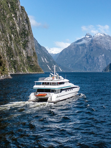 Cruise ship sailing through Milford Sound with mountain views.
