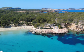 Coastline with clear blue waters and rocky shore in the Balearic Islands, Spain.