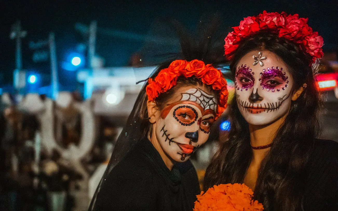 Women with Day of the Dead face paint and flower crowns at Mixquic celebration.