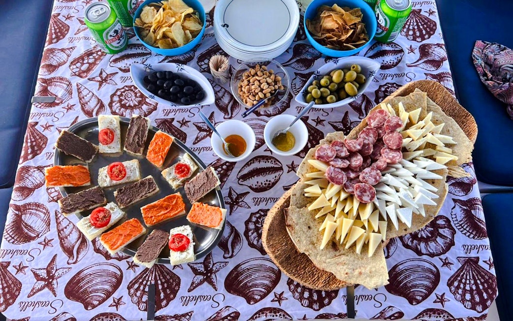 Assorted snacks and drinks on a table during a catamaran tour in La Maddalena Archipelago.
