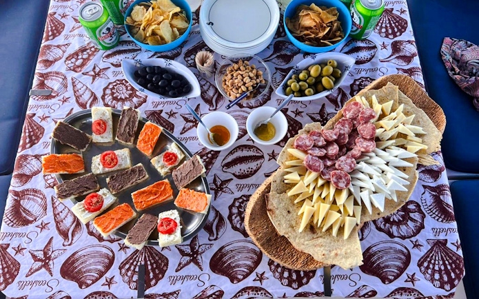 Assorted snacks and drinks on a table during a catamaran tour in La Maddalena Archipelago.