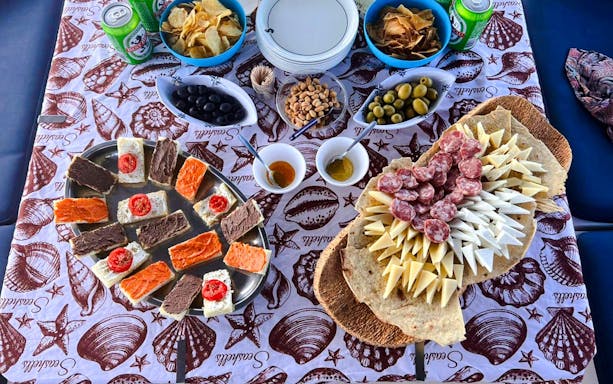 Assorted snacks and drinks on a table during a catamaran tour in La Maddalena Archipelago.