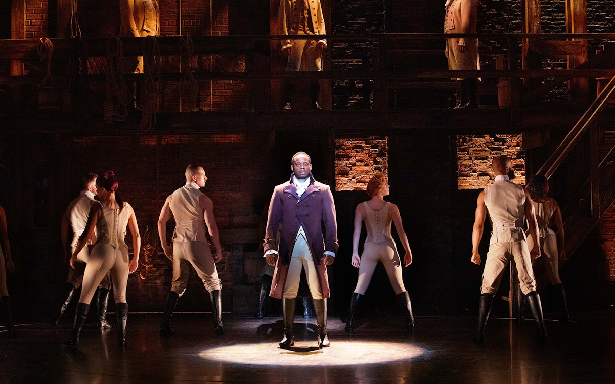 Stage performance of Hamilton with lead actor and ensemble cast.