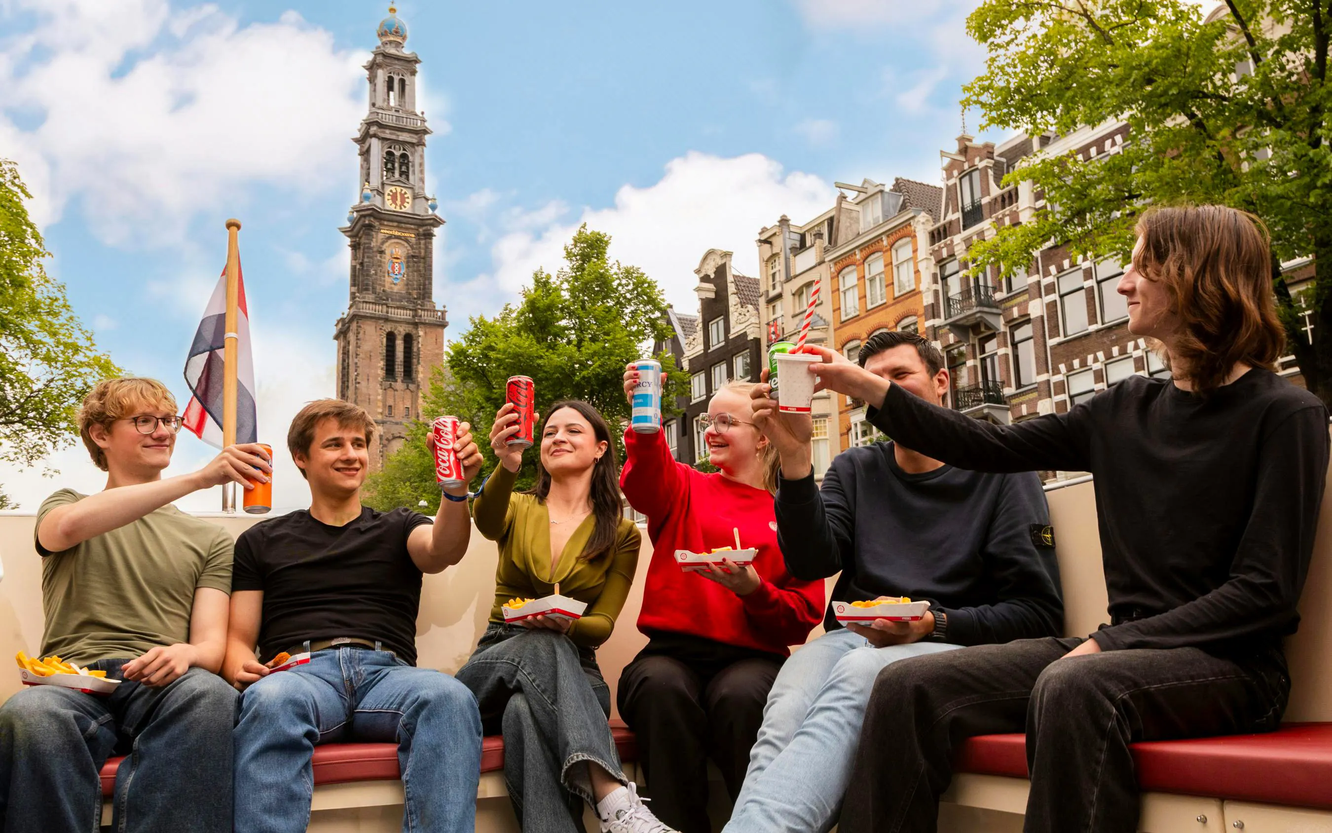 Guests enjoying snacks on an Amsterdam canal cruise with Westerkerk in the background.