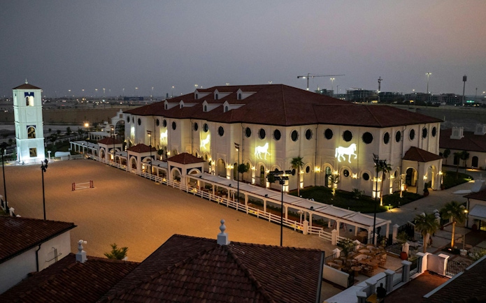 Abu Dhabi equestrian center with illuminated horse motifs at dusk.