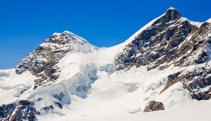 Hikers on Rottalsattel route with view of Jungfrau peak in Swiss Alps.