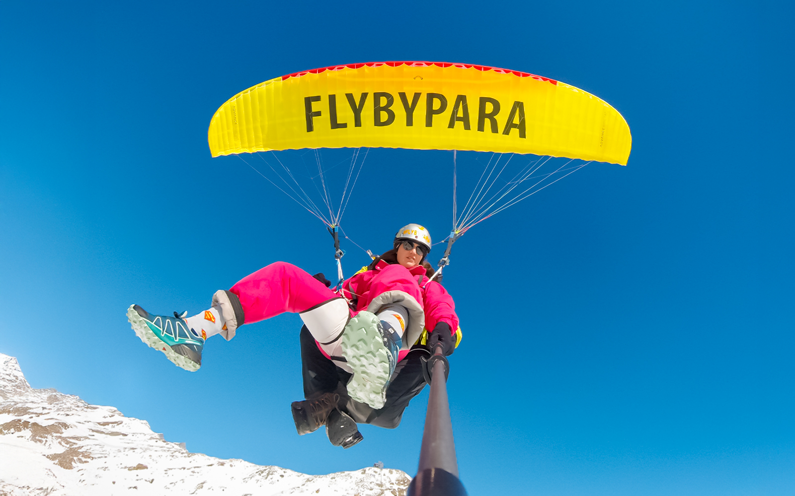 Tourist paragliding over Matterhorn Mountain with clear blue sky.