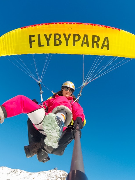 Tourist paragliding over Matterhorn Mountain with clear blue sky.