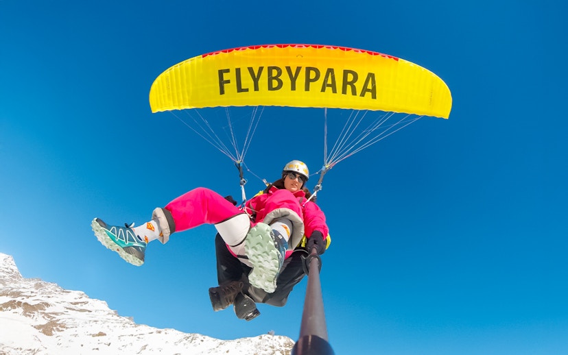 Tourist paragliding over Matterhorn Mountain with clear blue sky.