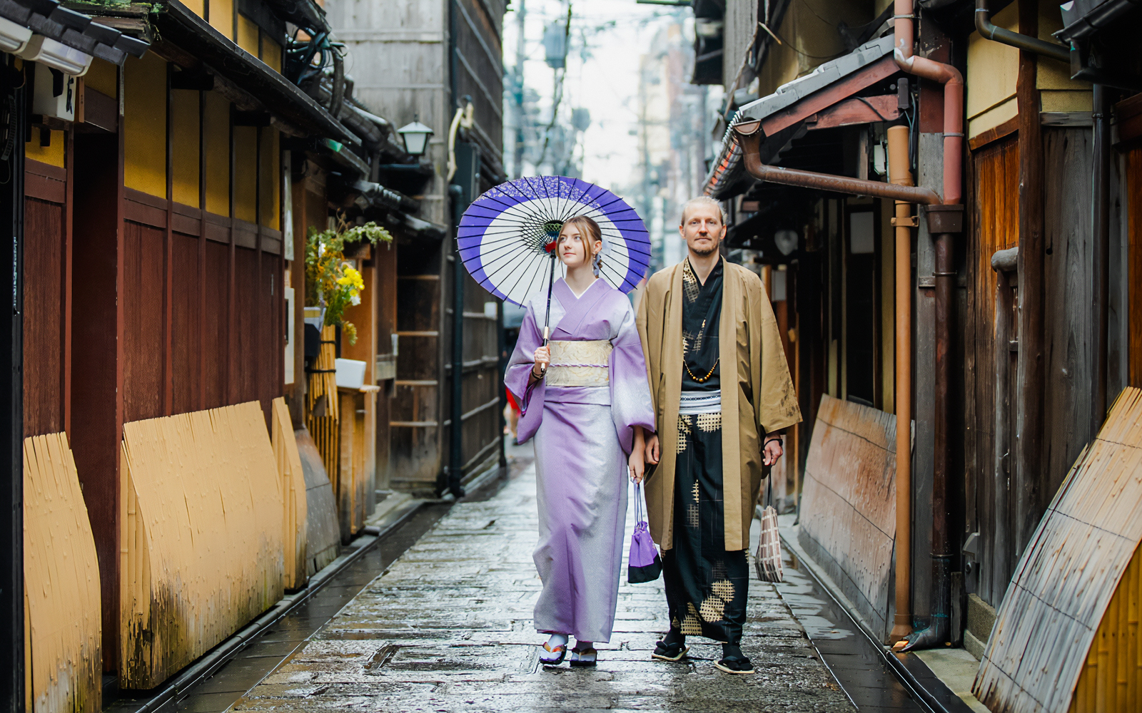 Couple in traditional kimono walking through historic Kyoto street.