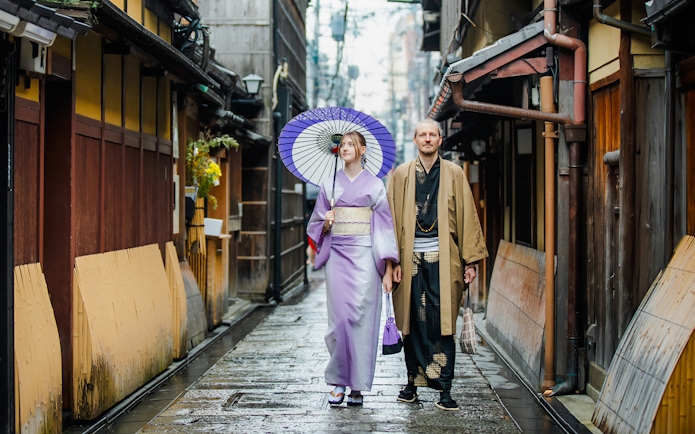 Couple in traditional kimono walking through historic Kyoto street.