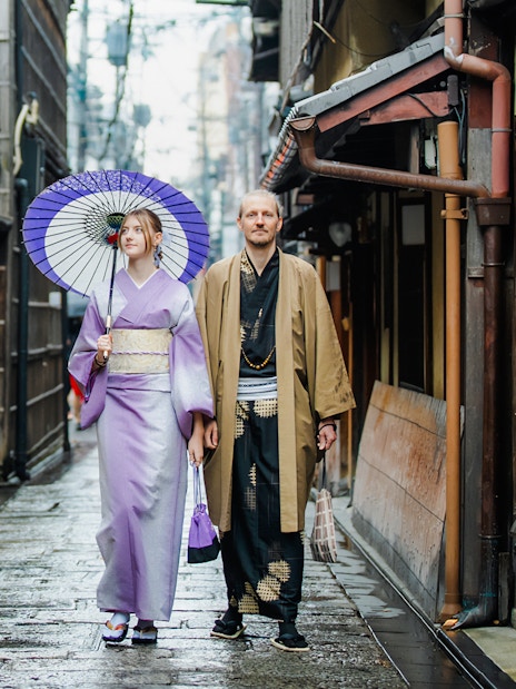 Couple in traditional kimono walking through historic Kyoto street.