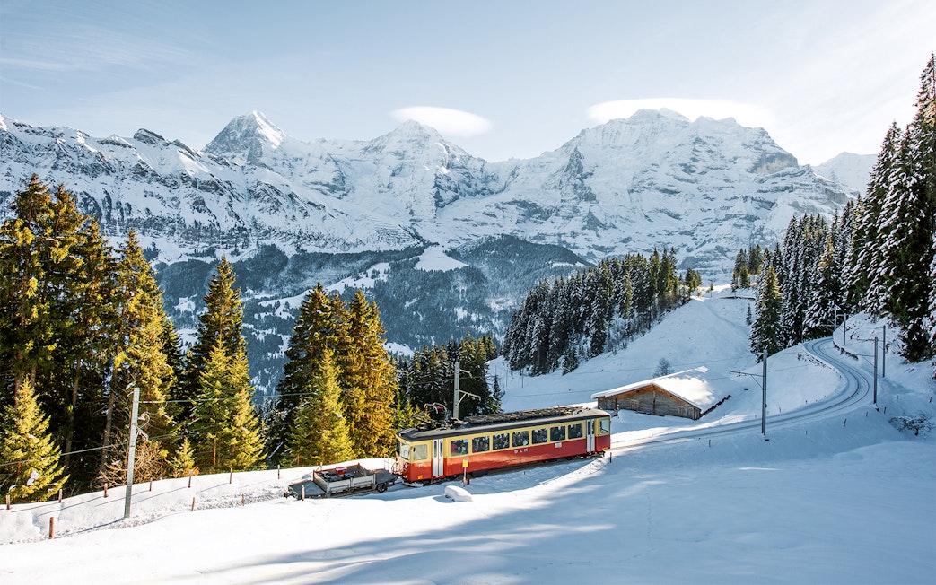 Lauterbrunnen-Mürren cableway train in snowy Swiss Alps landscape.