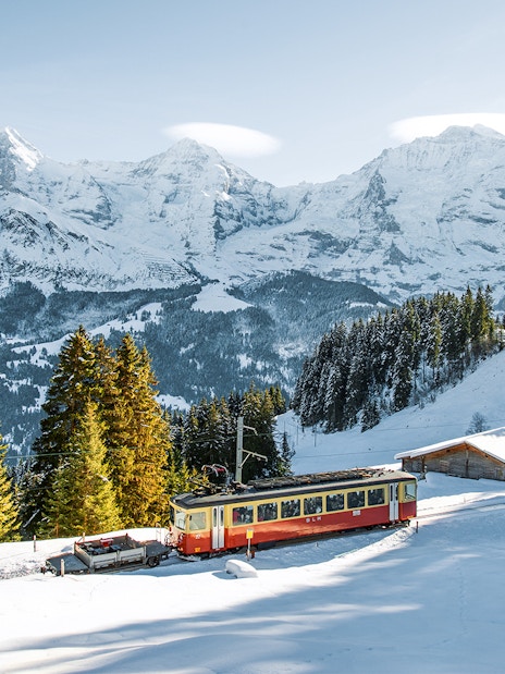 Lauterbrunnen-Mürren cableway train in snowy Swiss Alps landscape.