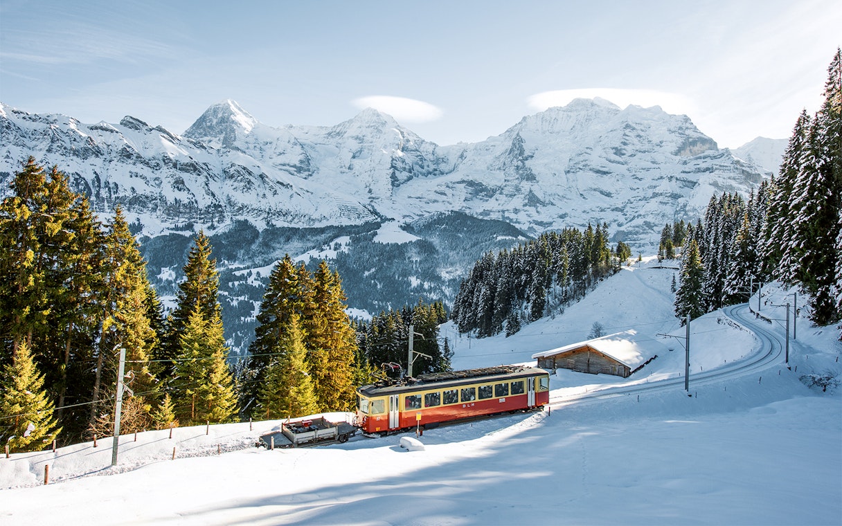 Lauterbrunnen-Mürren cableway train in snowy Swiss Alps landscape.