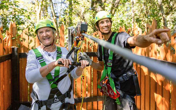 Two people preparing for a zipline adventure in Rotorua forest.