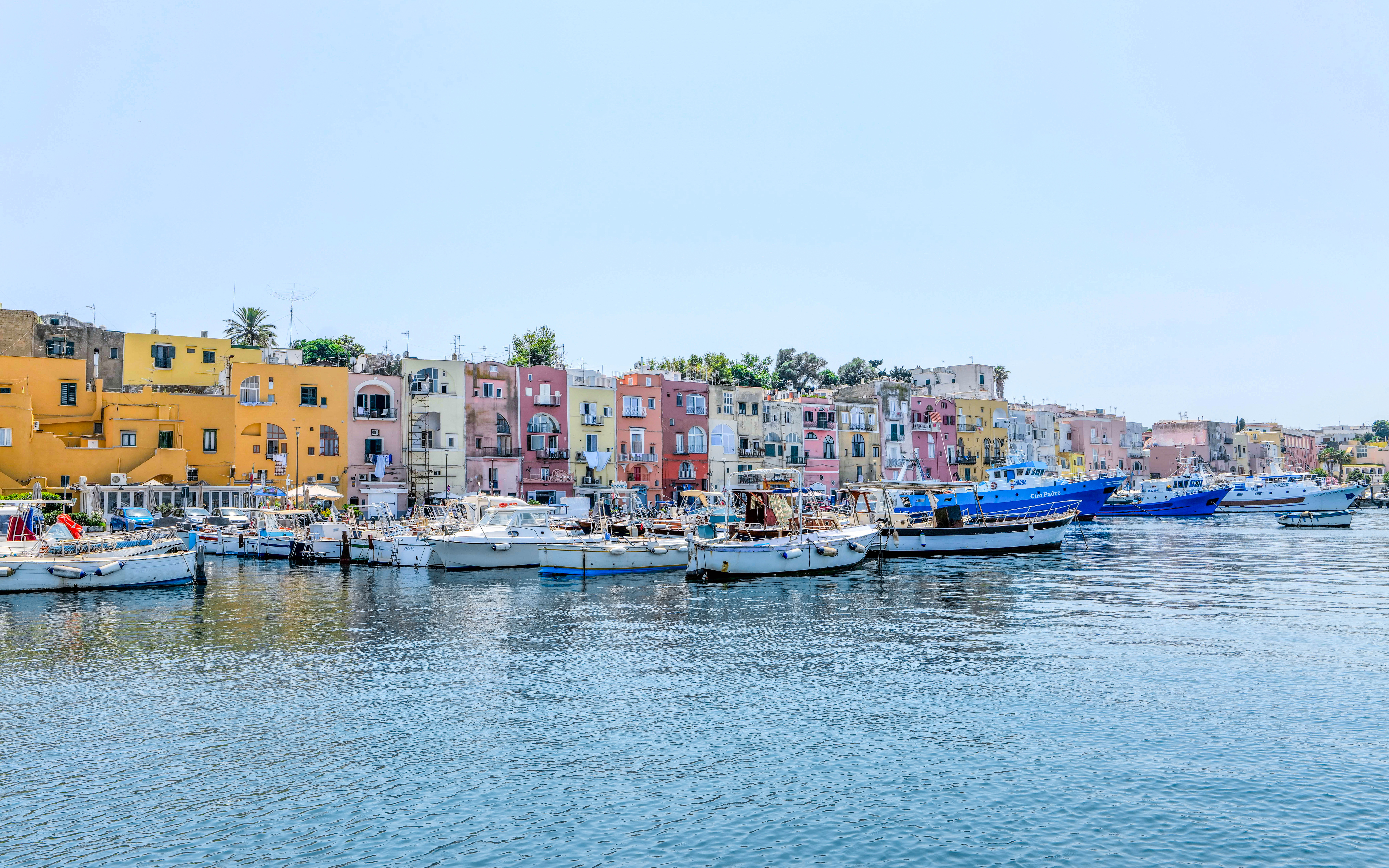 Boats docked in front of colorful buildings on Procida Island, Italy.