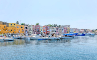 Boats docked in front of colorful buildings on Procida Island, Italy.