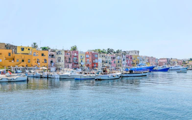 Boats docked in front of colorful buildings on Procida Island, Italy.