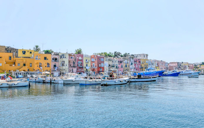 Boats docked in front of colorful buildings on Procida Island, Italy.