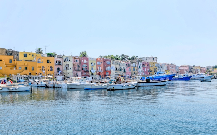 Boats docked in front of colorful buildings on Procida Island, Italy.