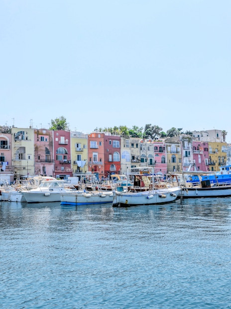 Boats docked in front of colorful buildings on Procida Island, Italy.