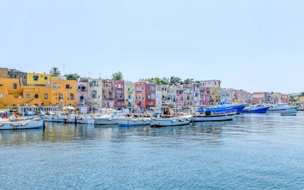 Boats docked in front of colorful buildings on Procida Island, Italy.