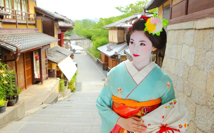 Maiko in traditional kimono on a historic street in Kyoto during a makeover photoshoot.