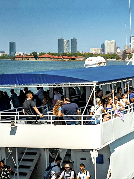 Tourists on a sightseeing cruise in New York Harbor with city skyline in the background.