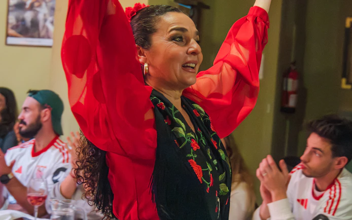 Flamenco dancer performing at Tablao La Cantaora, Seville, with audience clapping.