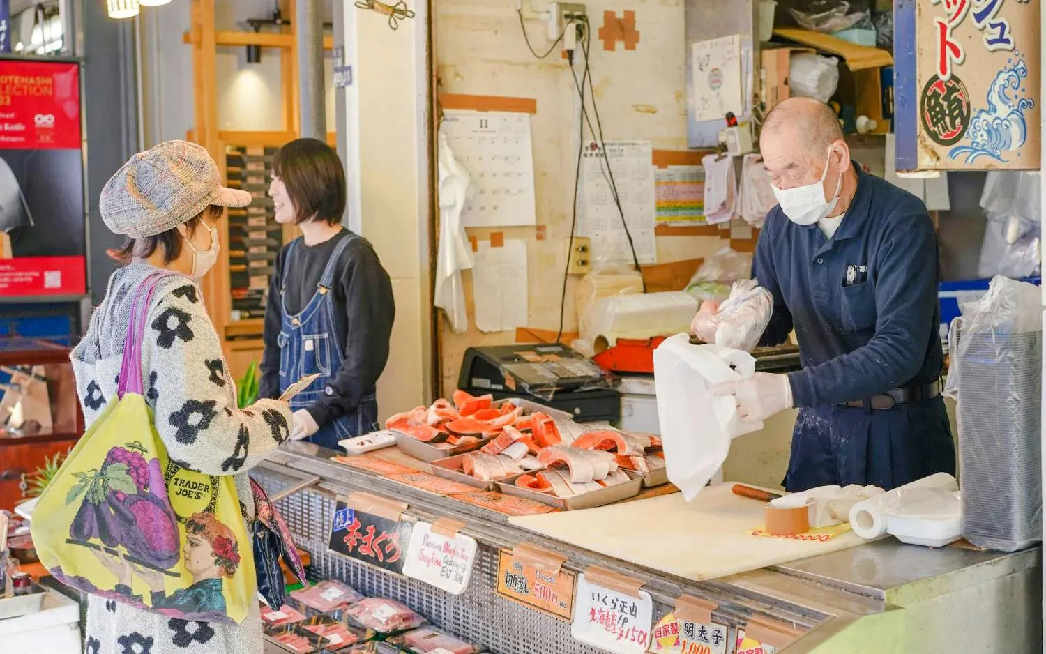 Storefront vendor at Tsukiji Fish Market preparing seafood for a customer.