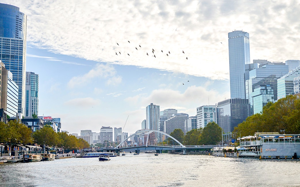 Melbourne skyline with boats on Yarra River during a river cruise.