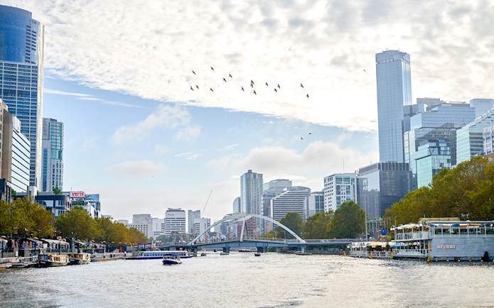 Melbourne skyline with boats on Yarra River during a river cruise.