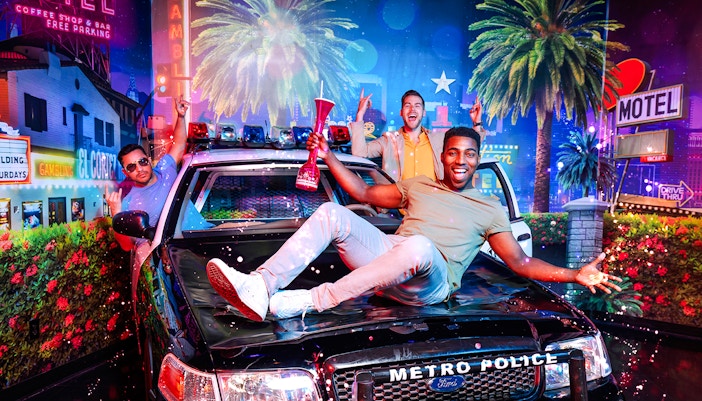 Guests posing with a police car at Madame Tussauds Las Vegas.