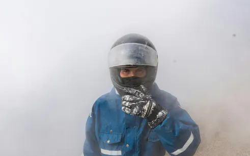 ATV rider in protective gear amidst volcanic steam, Reykjavik volcanic springs tour.