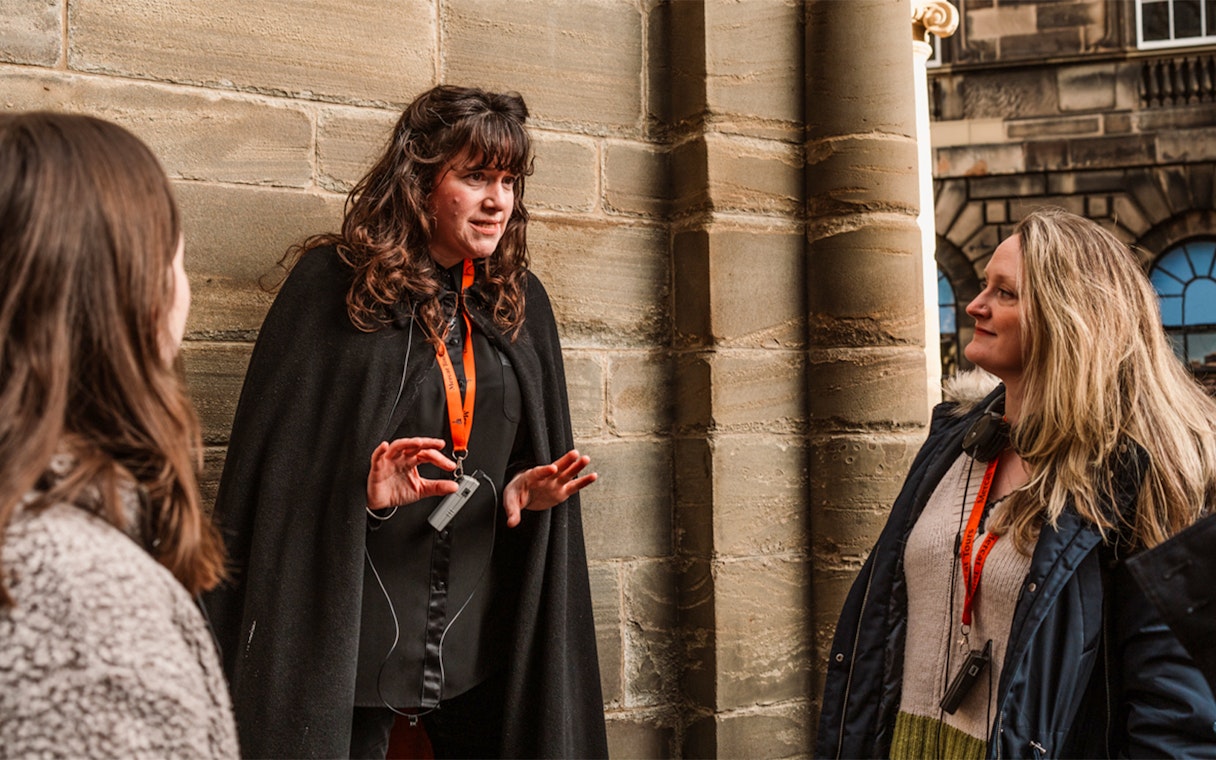 Tour guide leading Edinburgh's Royal Mile ghost tour with guests.