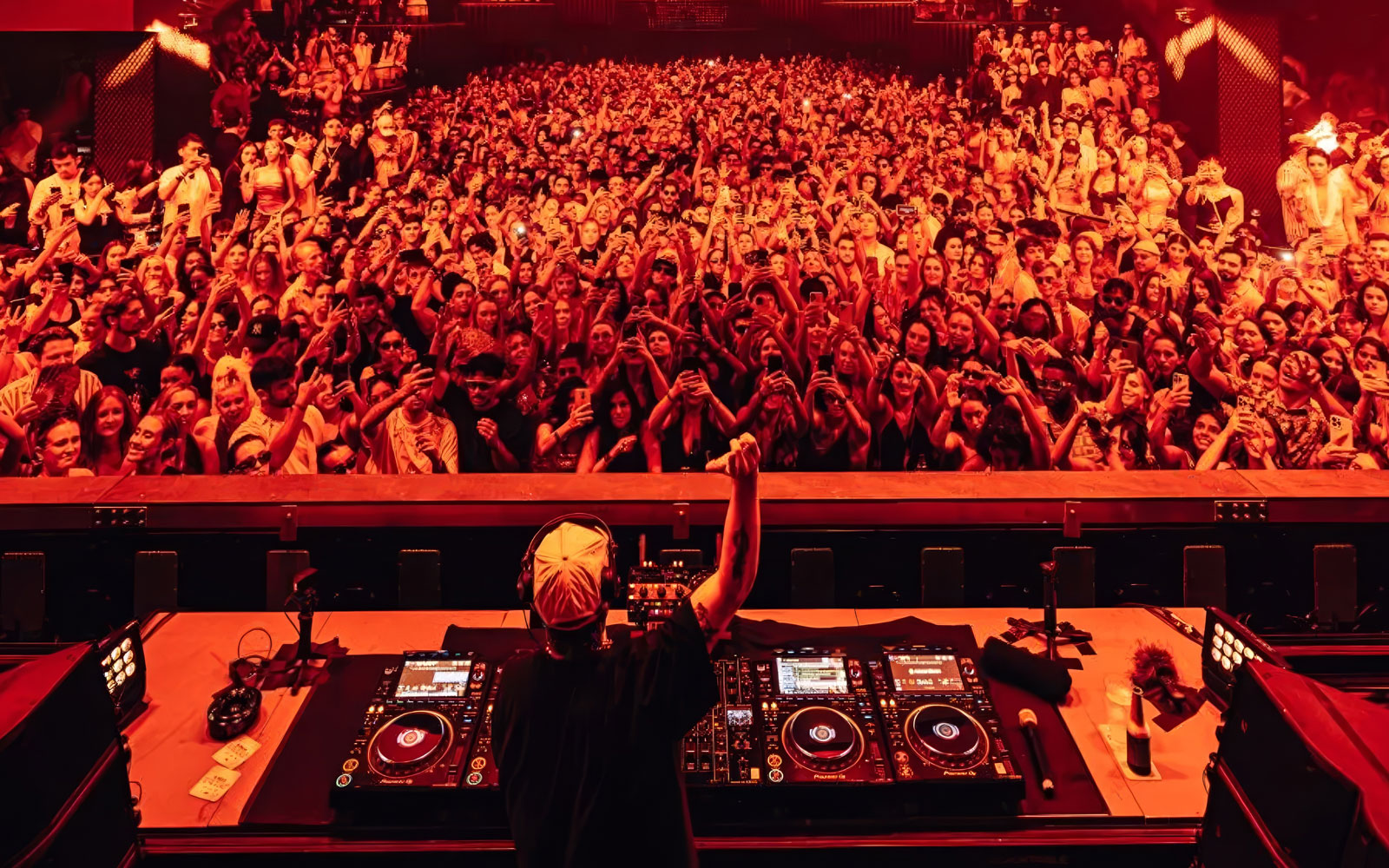 DJ performing to a large crowd at a Dom Dolla event in Ibiza.