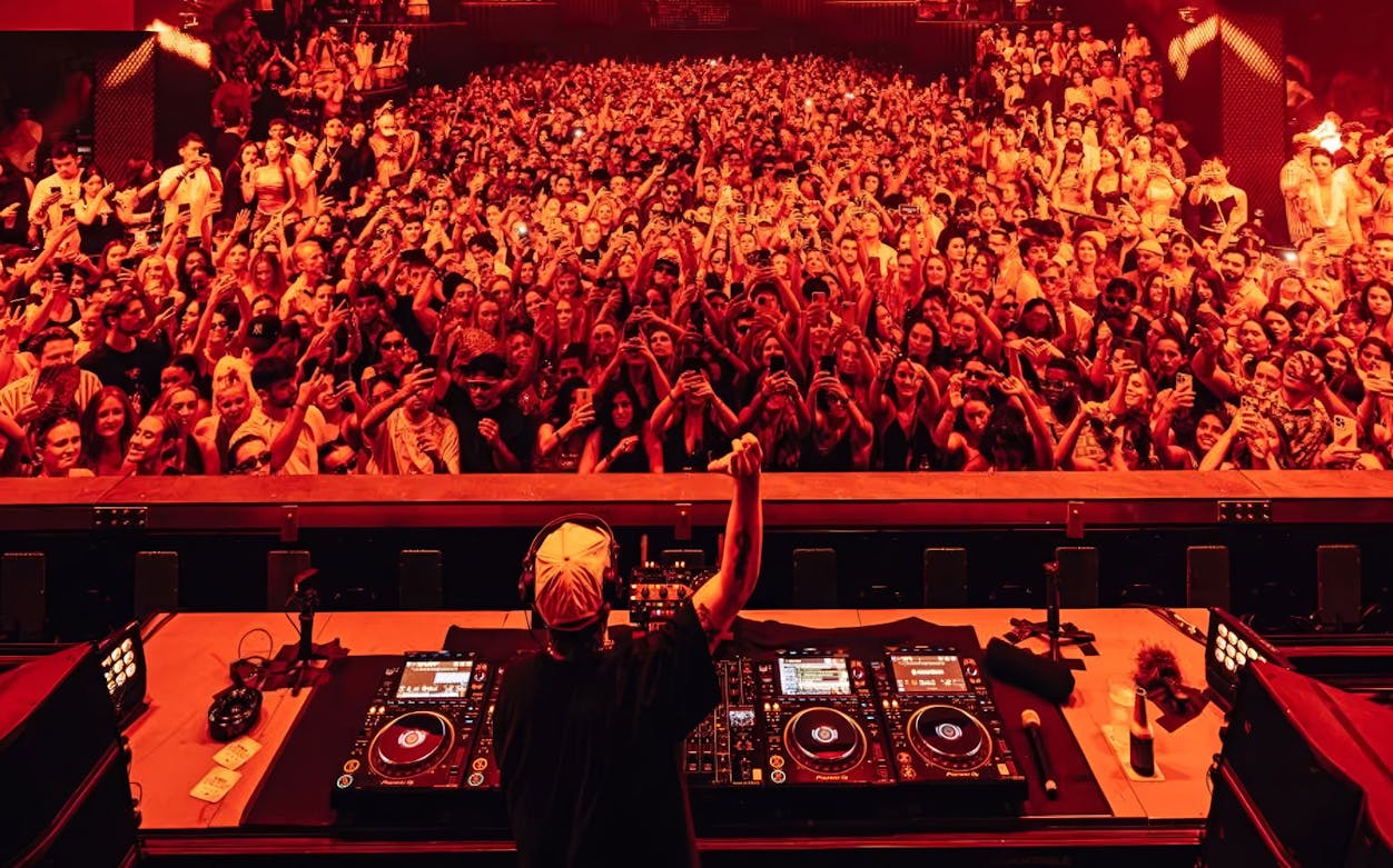 DJ performing to a large crowd at a Dom Dolla event in Ibiza.