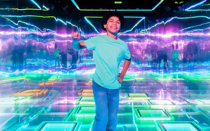 Child enjoying vibrant neon lights inside Dopamine Land.