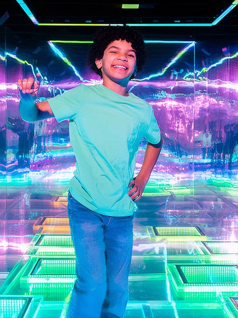 Child enjoying vibrant neon lights inside Dopamine Land.