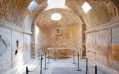 Ancient bathhouse interior in Pompeii with stone basin and vaulted ceiling.