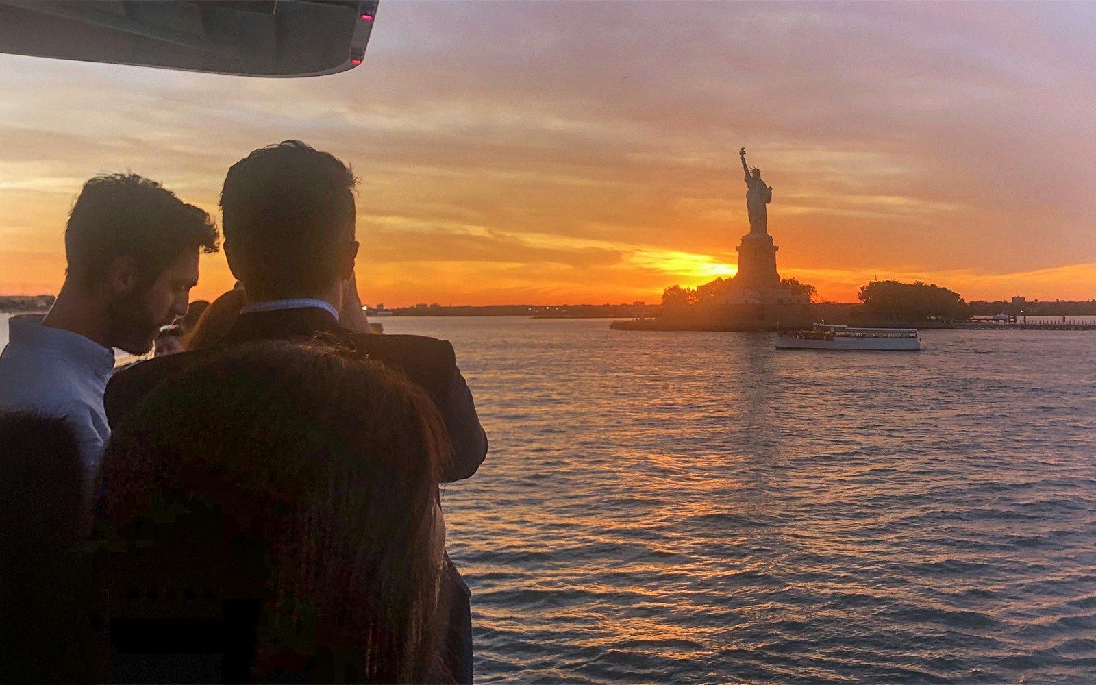 Statue of Liberty and Ellis Island at sunset during a scenic cruise.