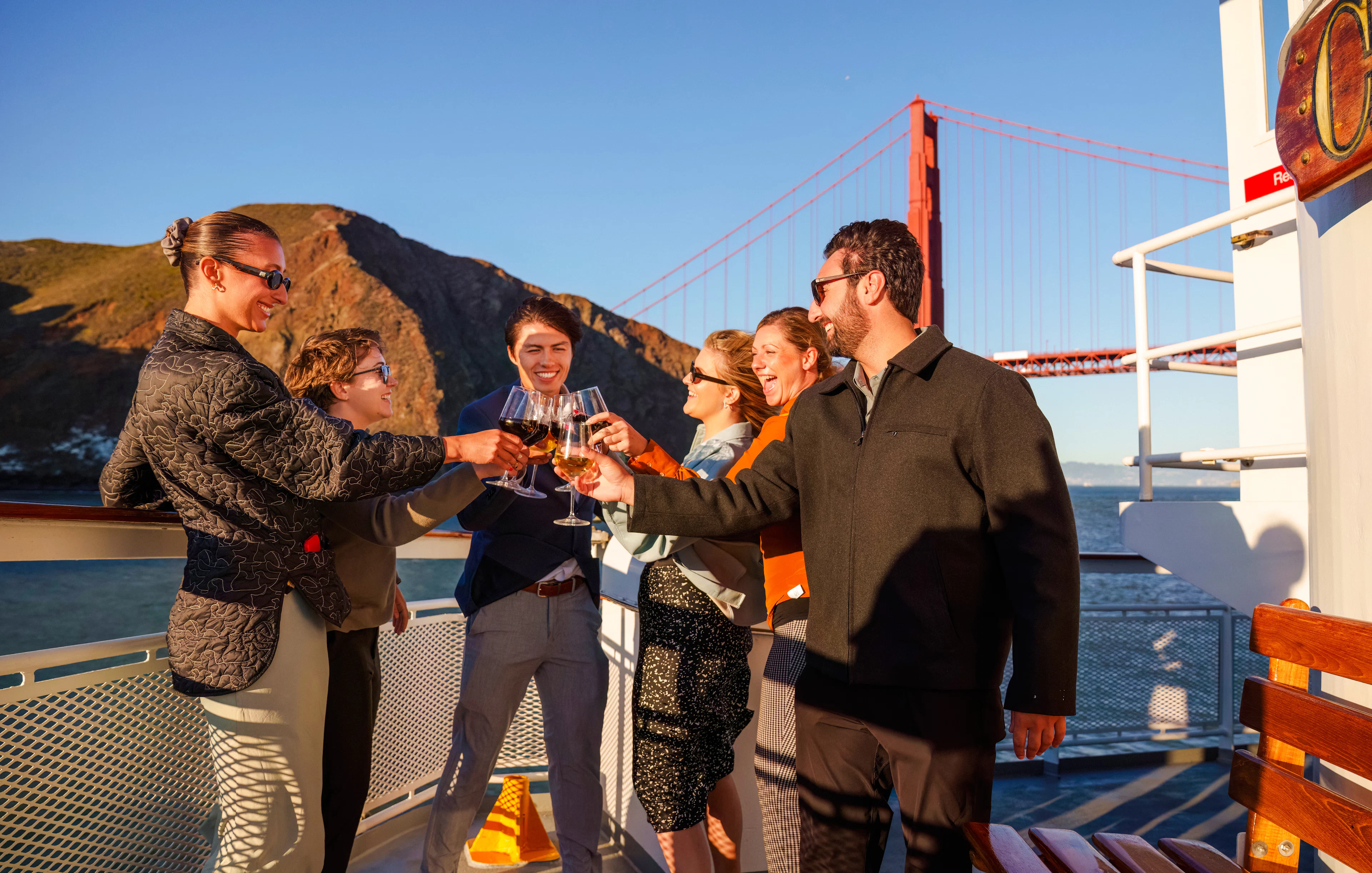 Group toasting on a San Francisco dinner cruise with Golden Gate Bridge in background.
