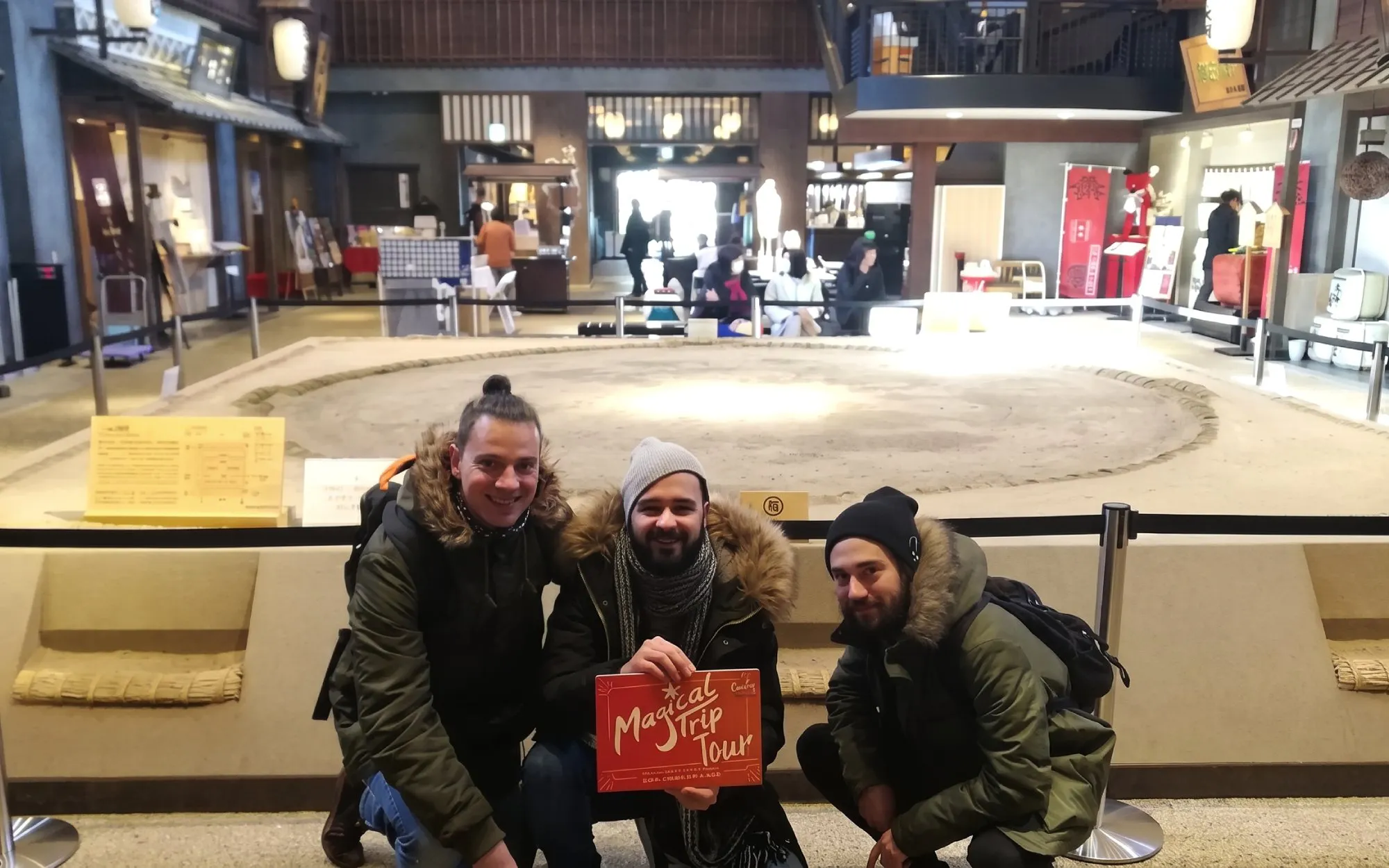 Visitors at Ryogoku Sumo Hall in Tokyo with sumo practice ring in the background.