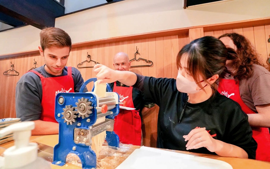 Participants making noodles in a Kyoto ramen and gyoza cooking class.